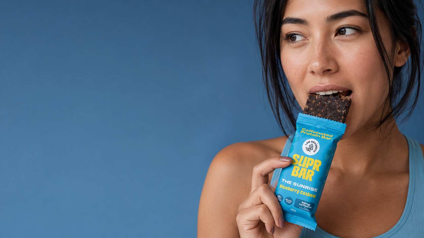 Woman eating I Am Grounded Blueberry Cashew SUPR Bar