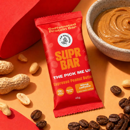 Supr Bar protein bar with espresso peanut butter flavor on a surface with peanuts and coffee beans.